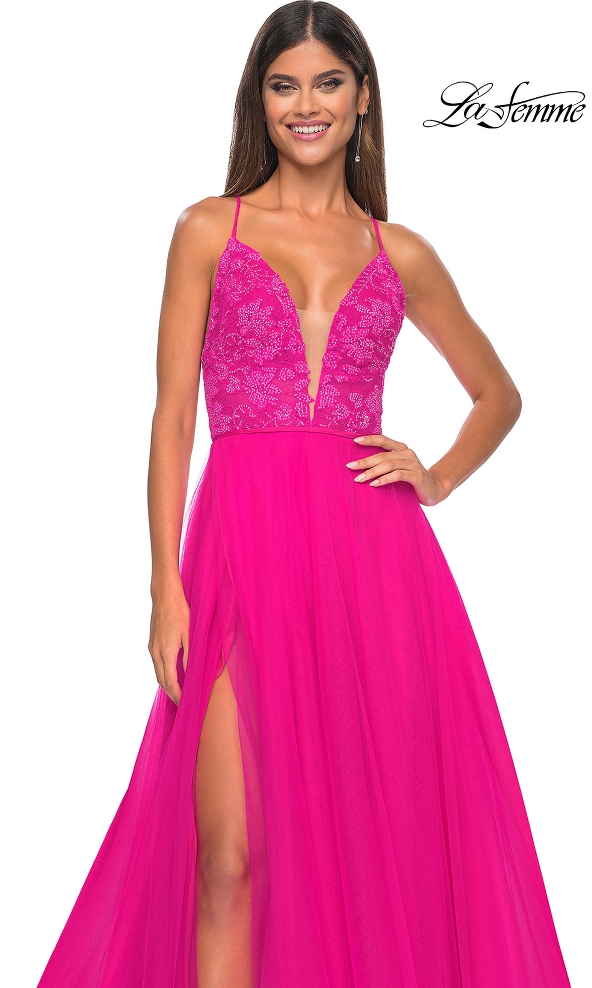 A woman models the La Femme Deep V-Neck Long Tulle Prom Gown 32059, featuring a bright pink lace bodice, deep V neckline, high slit, and elegant long tulle skirt, standing against a white background.